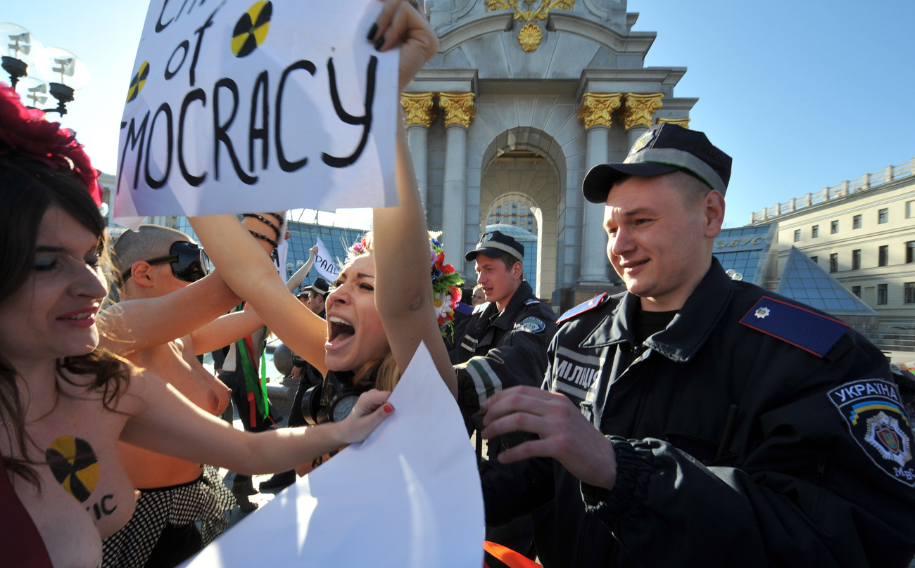 Rendőrök avatkoznak be a FEMEN tüntetésén - az aktivisták Kijevben protestálnak Viktor Janukovics elnök kormányának demokrácia-sértései ellen. A rendezvény egybeesett egy nemzetközi jótékonysági konferenciával, amelyet a csernobili atomerőmű maradványainak biztonságosabbá tételéért szerveztek.